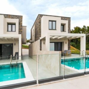 Summer Escapes Villa Verdant - Modern luxury homes with pools, stone accents, glass railings, and countryside views