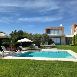 Summer Escapes Villa Moriai - Modern luxury home with turquoise pool, lounge chairs, umbrellas, manicured lawn and contemporary architecture