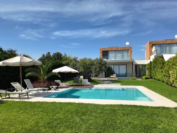 Summer Escapes Villa Moriai - Modern luxury home with turquoise pool, lounge chairs, umbrellas, manicured lawn and contemporary architecture